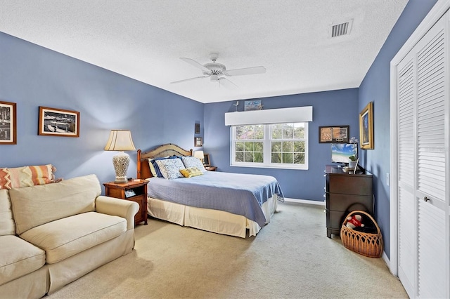 bedroom with baseboards, visible vents, a textured ceiling, carpet floors, and a closet