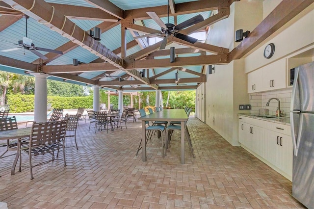 view of patio / terrace with area for grilling, a sink, a ceiling fan, a gazebo, and outdoor dining space