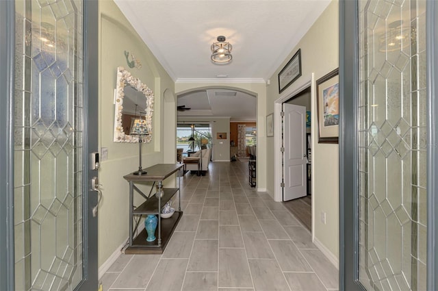 entrance foyer with baseboards, arched walkways, and crown molding