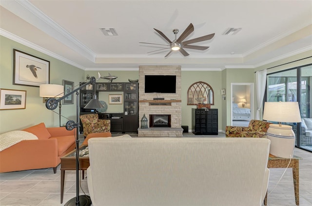 living area with ornamental molding, a stone fireplace, visible vents, and a ceiling fan