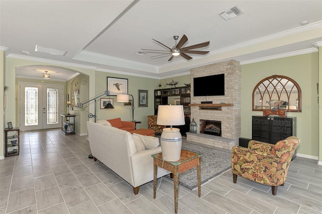 living area with visible vents, arched walkways, crown molding, french doors, and a fireplace