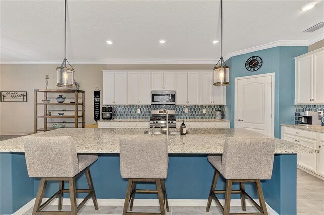 kitchen with stainless steel appliances, visible vents, backsplash, white cabinets, and a sink