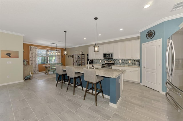 kitchen with visible vents, backsplash, appliances with stainless steel finishes, white cabinets, and a kitchen bar