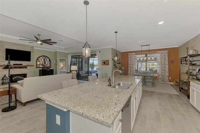 kitchen featuring crown molding, open floor plan, a sink, and a stone fireplace