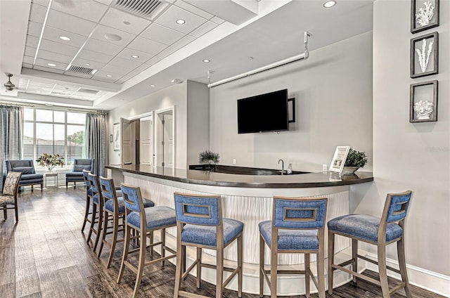 bar featuring indoor wet bar, visible vents, and wood finished floors