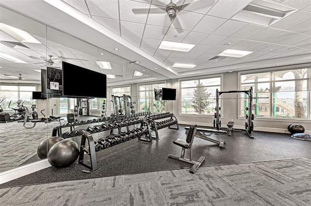 gym with ceiling fan, a drop ceiling, and baseboards