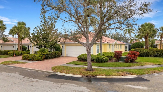 view of front of house featuring a tiled roof, an attached garage, decorative driveway, a front yard, and stucco siding