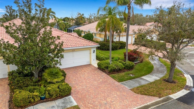 mediterranean / spanish-style home featuring a garage, a tiled roof, decorative driveway, and stucco siding