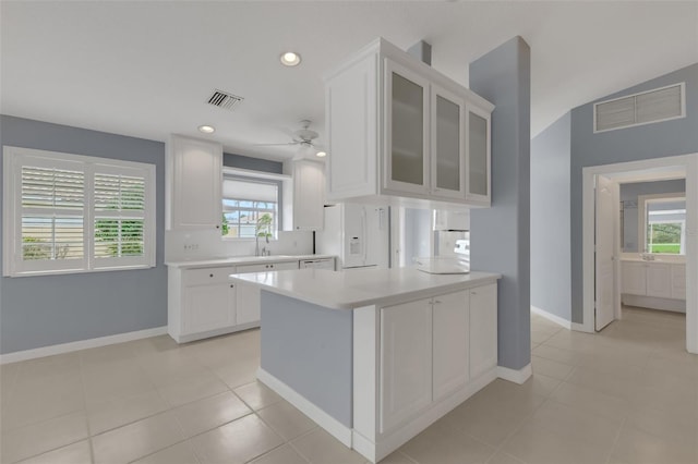 kitchen featuring white fridge with ice dispenser, light countertops, visible vents, and white cabinets