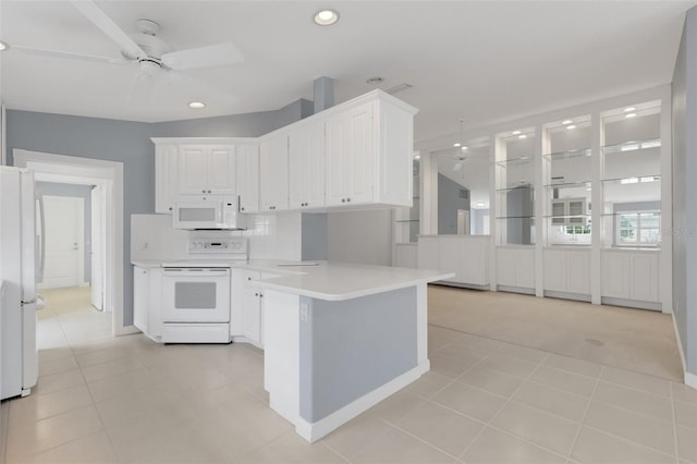 kitchen with a peninsula, white appliances, a ceiling fan, and white cabinetry