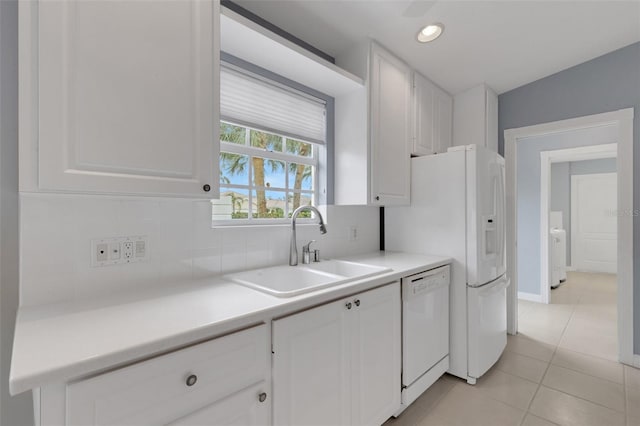 kitchen featuring light tile patterned floors, decorative backsplash, white cabinets, white dishwasher, and a sink