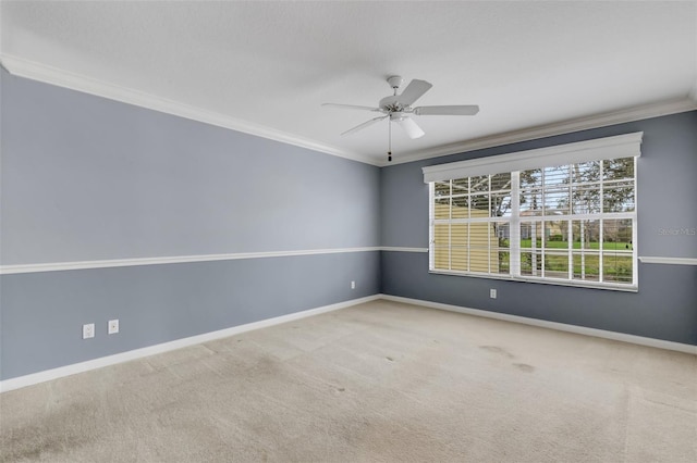 carpeted spare room with a ceiling fan, crown molding, and baseboards