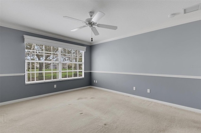 spare room with carpet floors, ornamental molding, a ceiling fan, and baseboards