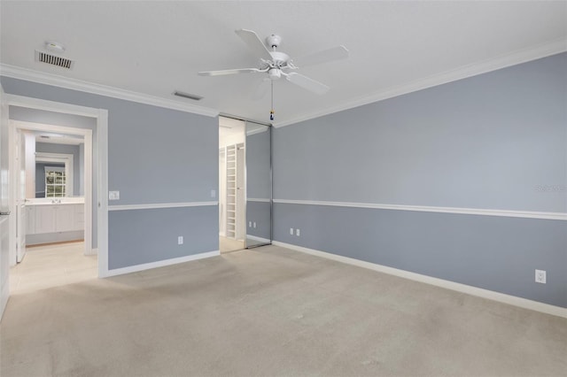 carpeted spare room with a ceiling fan, visible vents, crown molding, and baseboards