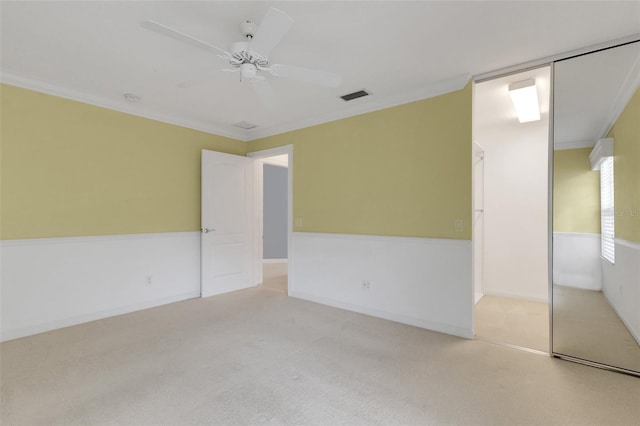 spare room featuring light carpet, ceiling fan, visible vents, and ornamental molding