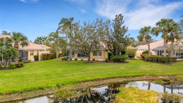 back of property featuring a lawn, a water view, and a lanai