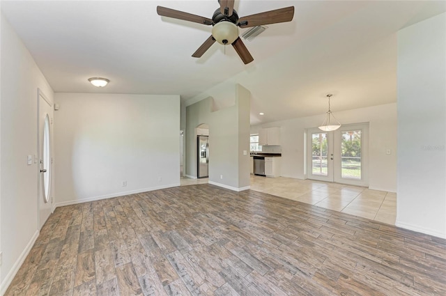 unfurnished living room with light wood-style floors, baseboards, vaulted ceiling, and a ceiling fan