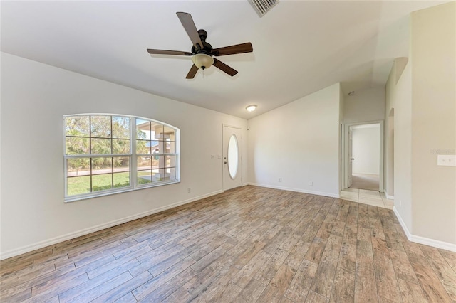 spare room with vaulted ceiling, light wood-type flooring, visible vents, and a ceiling fan