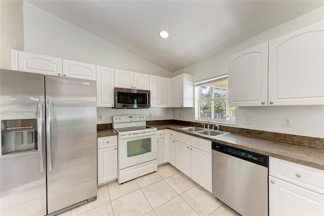 kitchen with light tile patterned floors, a sink, white cabinets, appliances with stainless steel finishes, and dark countertops