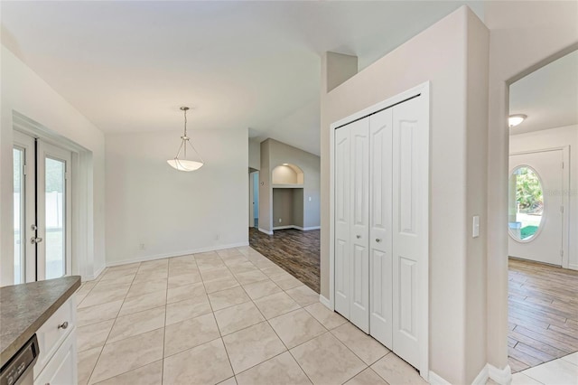 interior space with lofted ceiling, light tile patterned flooring, and baseboards