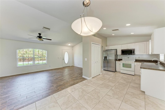 kitchen with appliances with stainless steel finishes, dark countertops, visible vents, and a sink