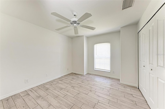 unfurnished bedroom with a closet, visible vents, ceiling fan, light wood-type flooring, and baseboards