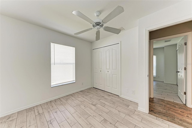 unfurnished bedroom featuring light wood finished floors, a closet, visible vents, ceiling fan, and baseboards