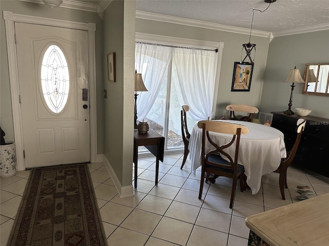 foyer with crown molding, a textured ceiling, baseboards, and light tile patterned floors