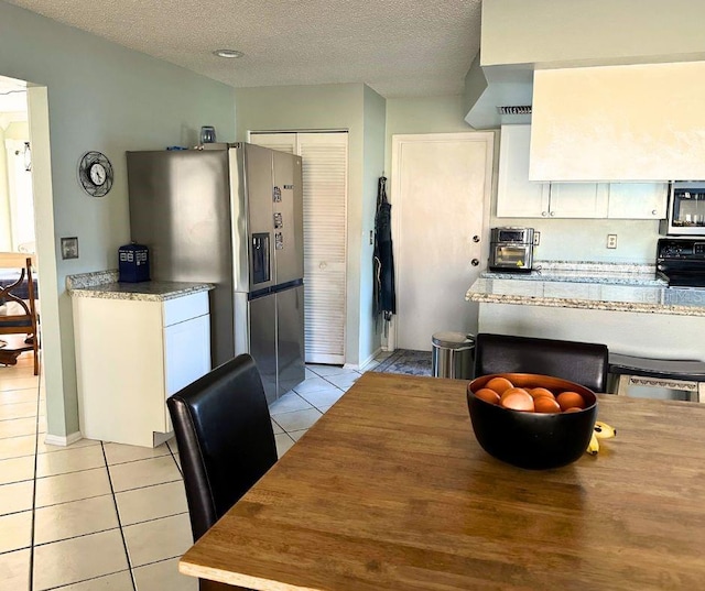 1805 Springwood Dr, Sarasota, FL 34232 - kitchen with appliances with stainless steel finishes, light tile patterned floors, a textured ceiling, white cabinetry, and baseboards