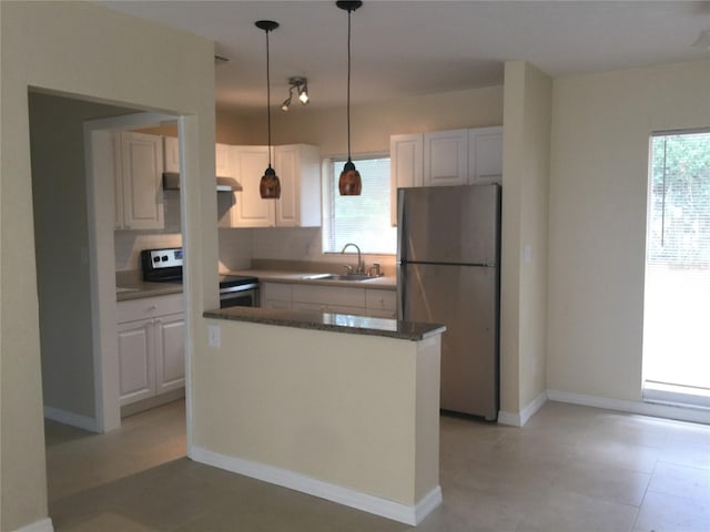 kitchen featuring white cabinets, stainless steel appliances, a sink, and decorative light fixtures