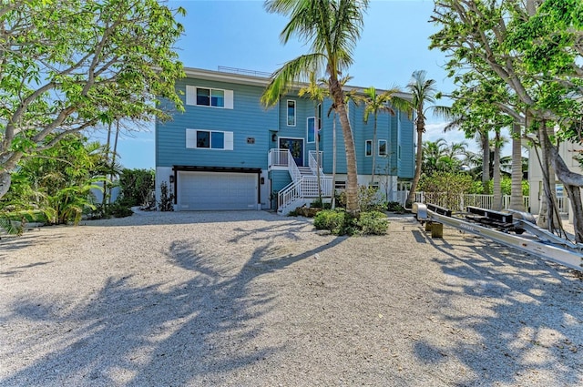 view of front of property with gravel driveway, an attached garage, and stairs