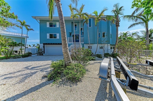 view of front of property featuring driveway, stairs, a garage, and fence