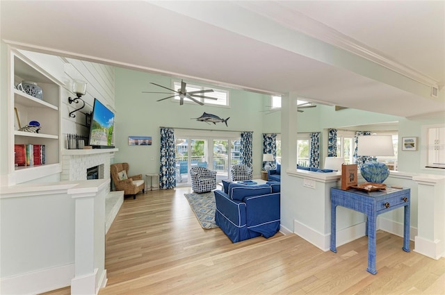 living area featuring a brick fireplace, light wood-style flooring, and ceiling fan