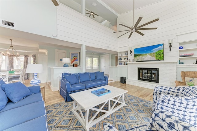 living area with a fireplace, wood finished floors, visible vents, and built in features