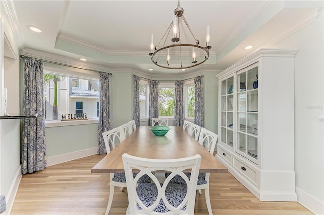 dining room with light wood finished floors, baseboards, a raised ceiling, ornamental molding, and a chandelier