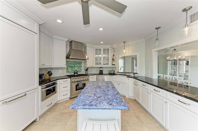 kitchen with wall chimney range hood, a sink, appliances with stainless steel finishes, and tasteful backsplash