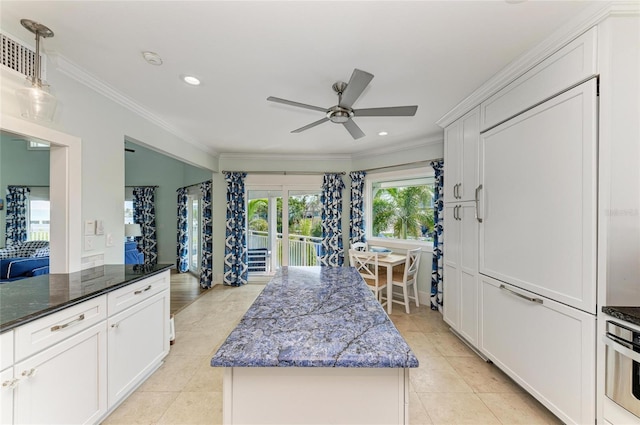 kitchen featuring a center island, light tile patterned floors, ornamental molding, white cabinets, and ceiling fan