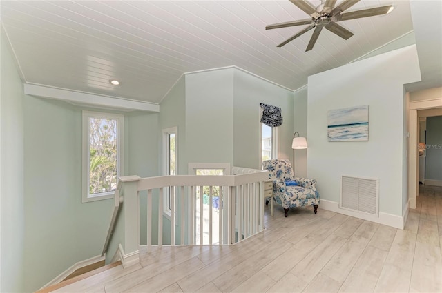 hallway with lofted ceiling, wood finished floors, an upstairs landing, visible vents, and baseboards