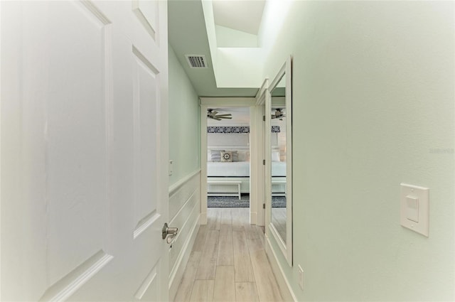 hall with light wood-style floors and visible vents