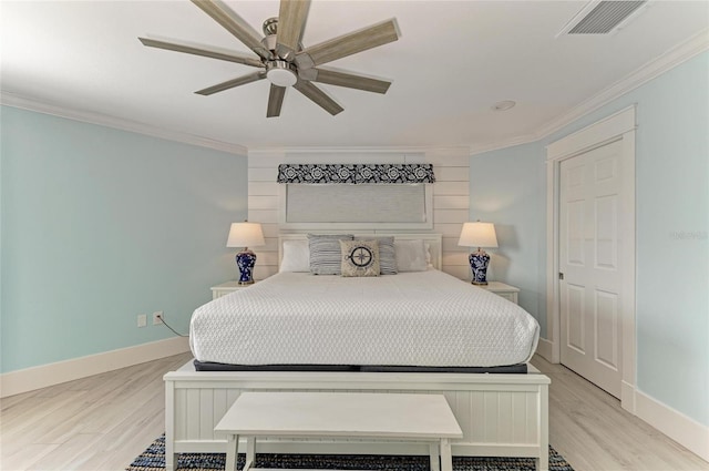 bedroom with ornamental molding, light wood-style flooring, visible vents, and baseboards