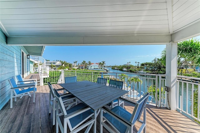 wooden deck with a water view and outdoor dining space