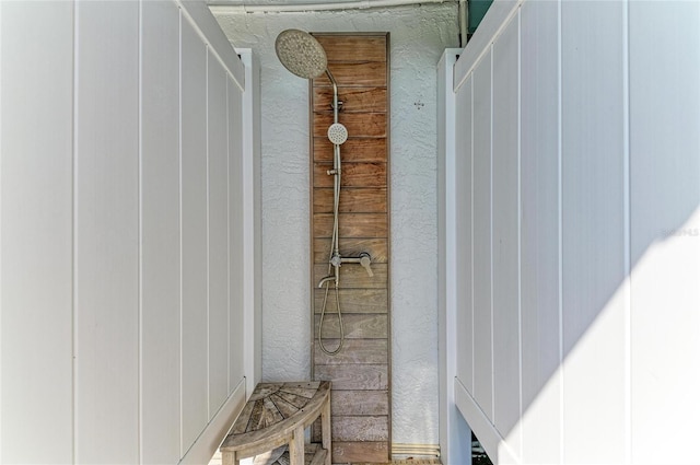 full bath with a textured wall and tiled shower