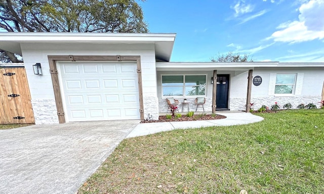 view of front of home featuring an attached garage, concrete block siding, concrete driveway, and a front yard