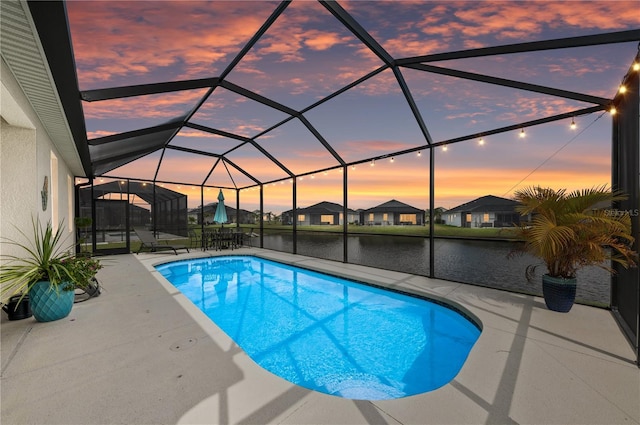 pool at dusk featuring glass enclosure, an outdoor pool, and a patio