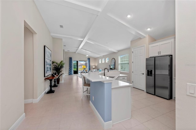 kitchen with lofted ceiling with beams, white cabinetry, light countertops, stainless steel fridge with ice dispenser, and a large island with sink