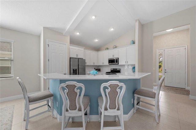 kitchen with light tile patterned floors, appliances with stainless steel finishes, a breakfast bar, and white cabinets