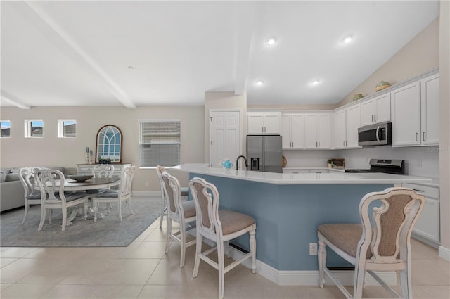 kitchen with light countertops, appliances with stainless steel finishes, white cabinetry, and a kitchen breakfast bar