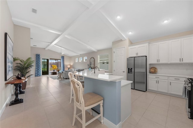 kitchen featuring appliances with stainless steel finishes, open floor plan, lofted ceiling with beams, and light tile patterned floors