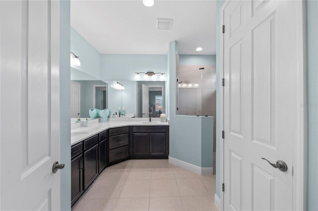 full bath featuring double vanity, baseboards, tile patterned flooring, a tile shower, and a sink