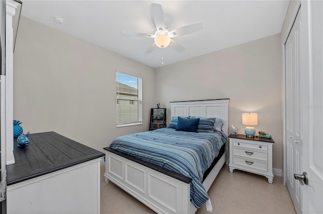 bedroom featuring light tile patterned floors, ceiling fan, a closet, and baseboards